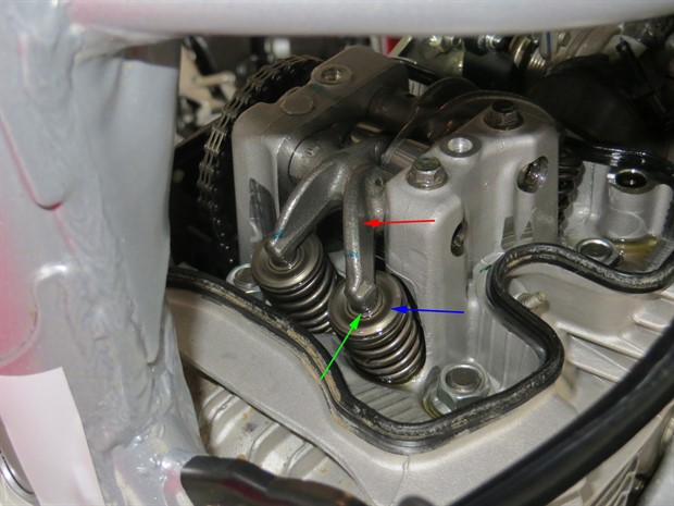 Rocker arms (red), shims (green) and valve spring retainer (blue arrow)