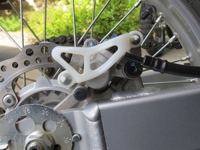 CRF250F rear brake caliper with guard in place.